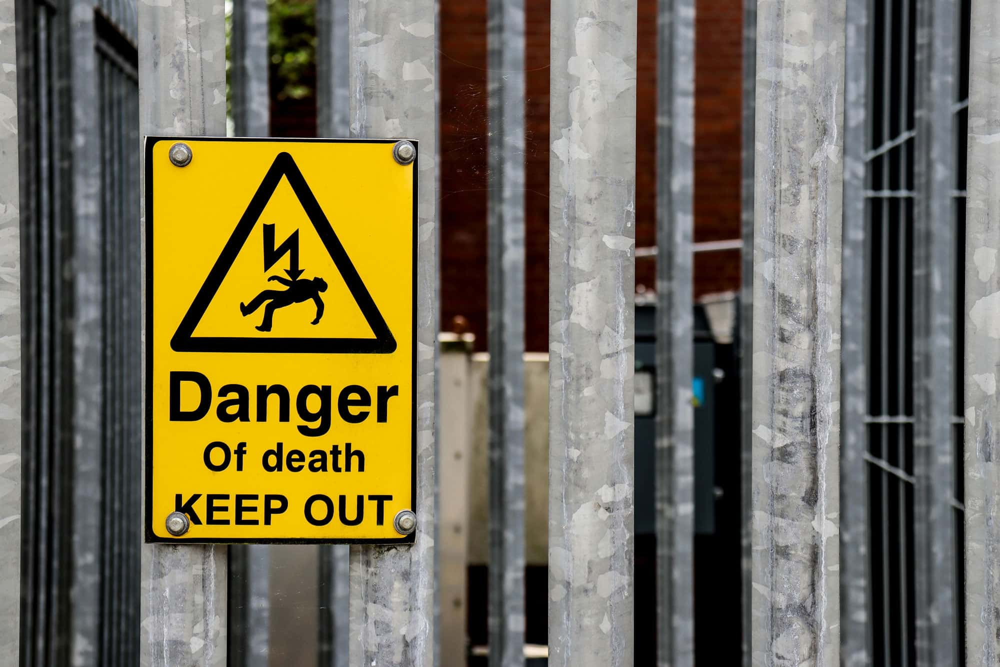 Warnschild mit der Aufschrift 'Danger of death, Keep Out' an einem Metallzaun.